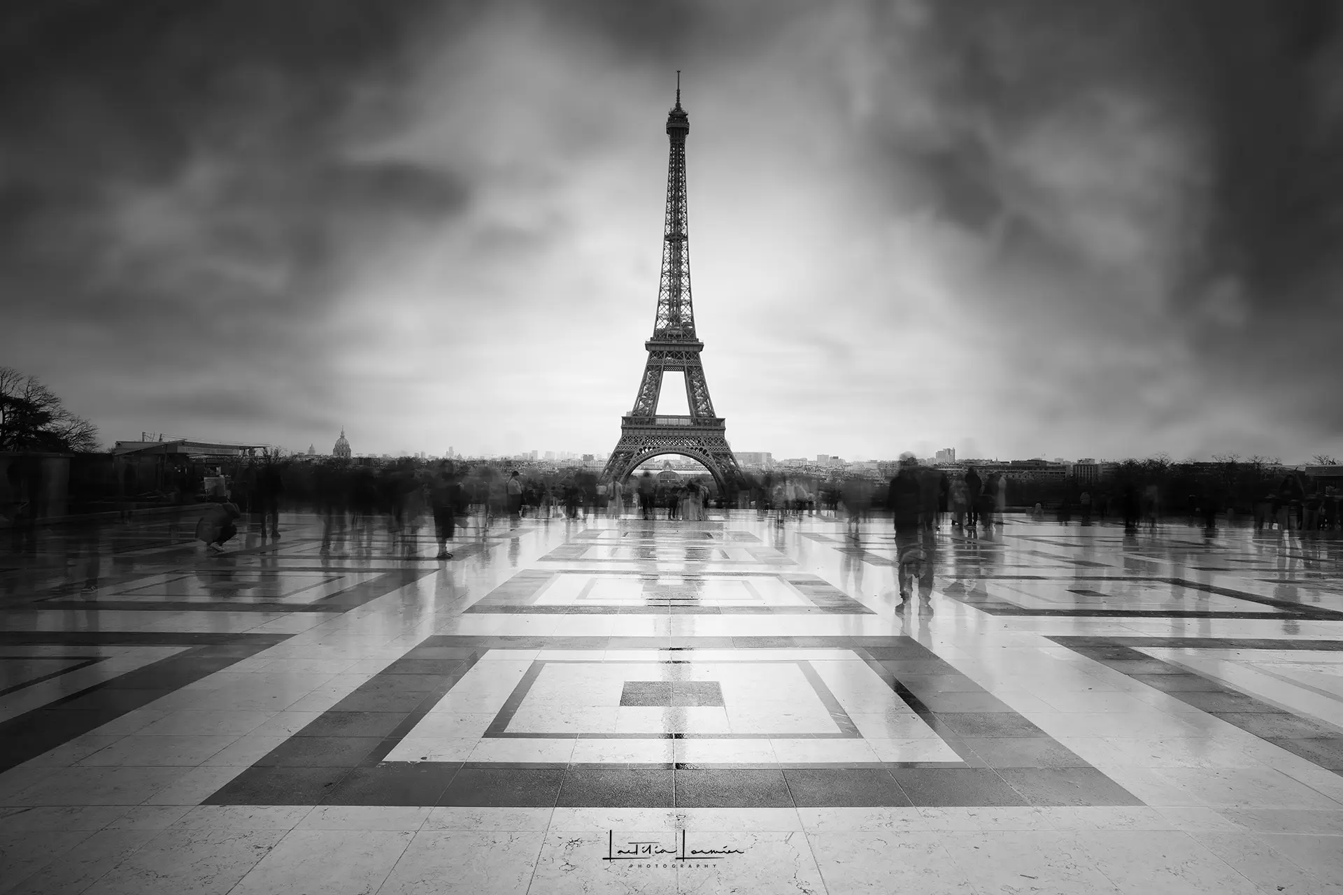 Photographie en noir et blanc de la Tour Eiffel capturée en pose longue depuis le Trocadéro, avec un effet de filé dans le ciel.